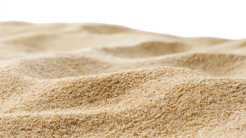 Close-up of dry beach sand with undulating ripples filling the frame against a white background