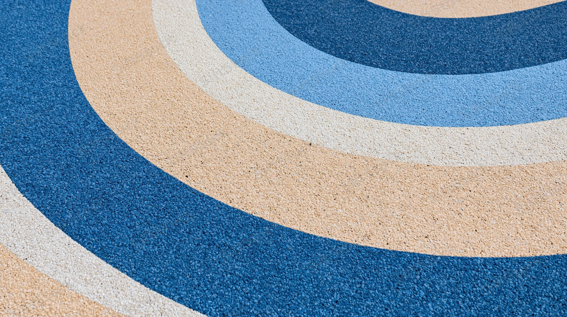 Close-up of blue beige and white circular patterned rubber playground surface
