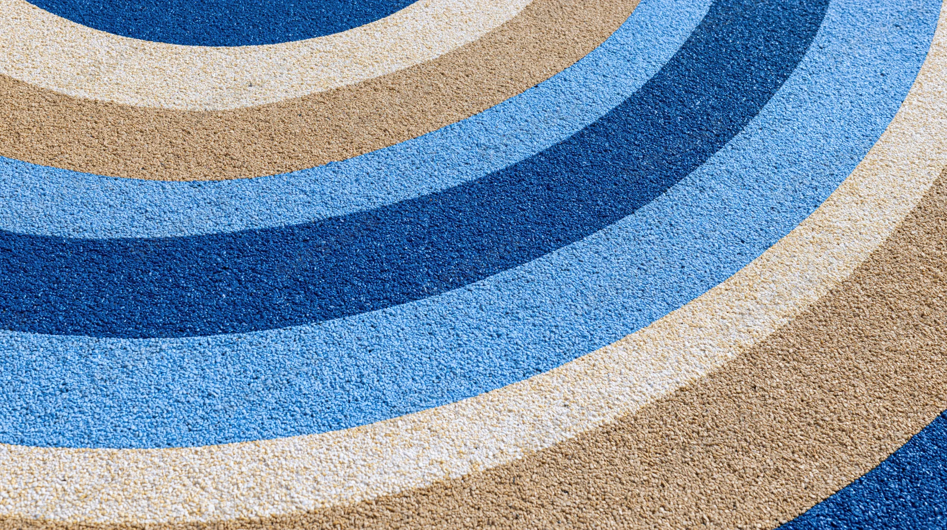 Close-up overhead view of a blue and beige striped rubber playground surface