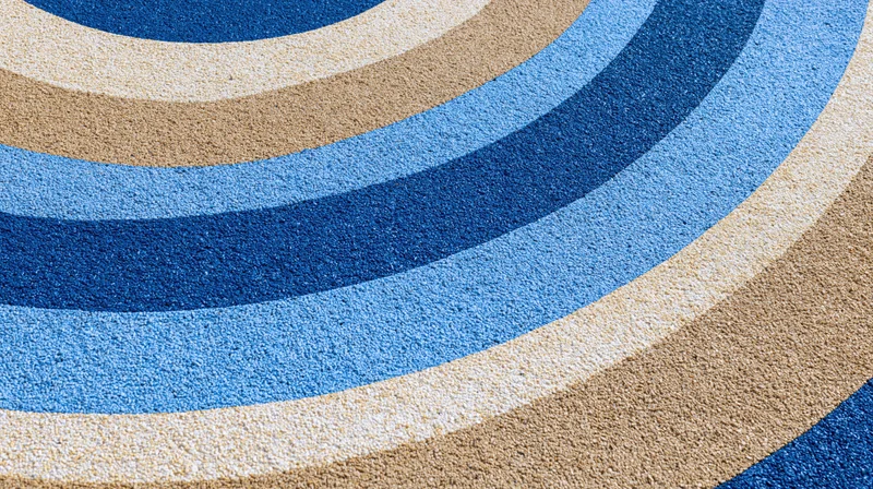 Close-up overhead view of a blue and beige striped rubber playground surface