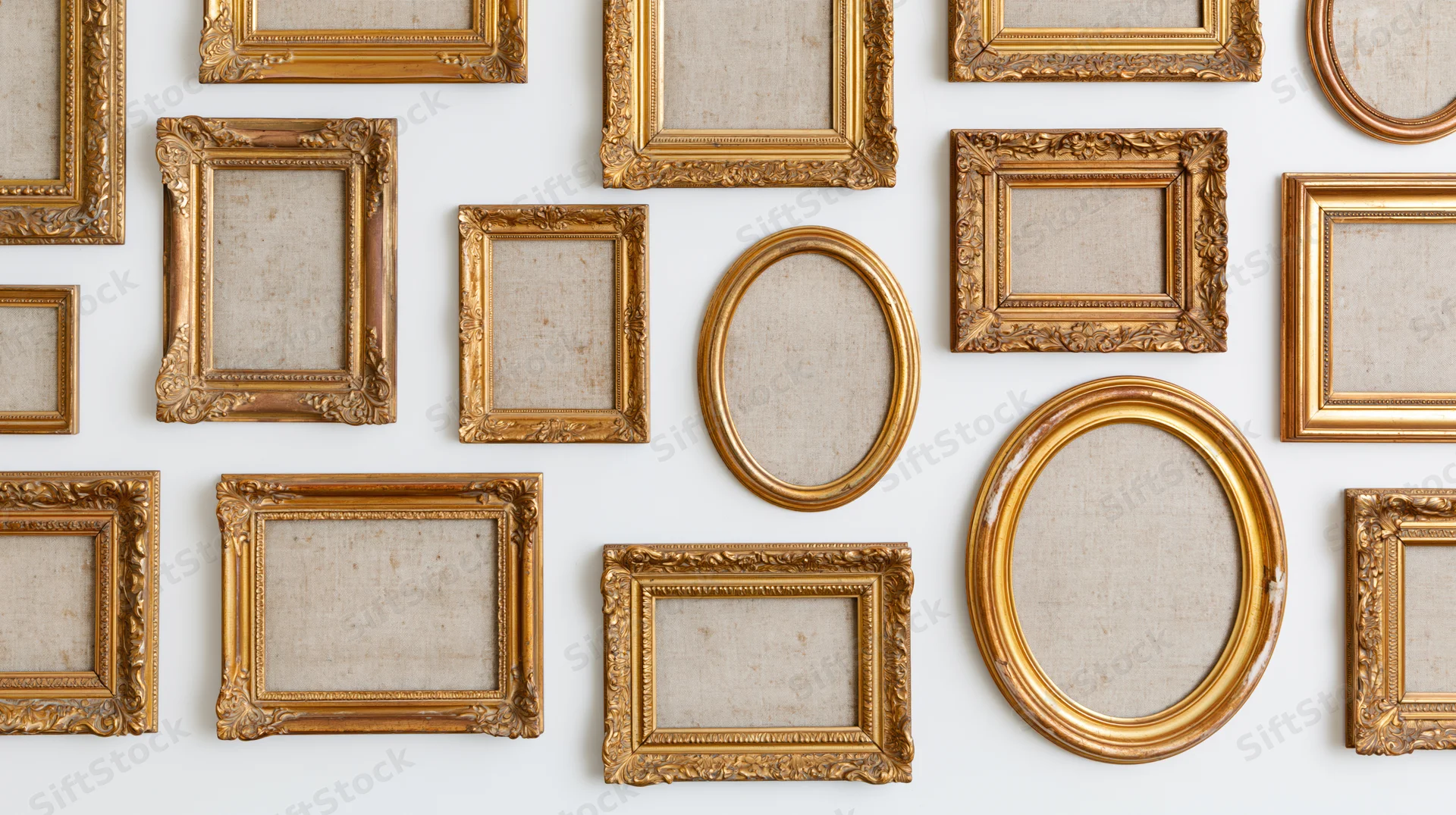 Antique gold picture frames arranged in a grid on a white wall