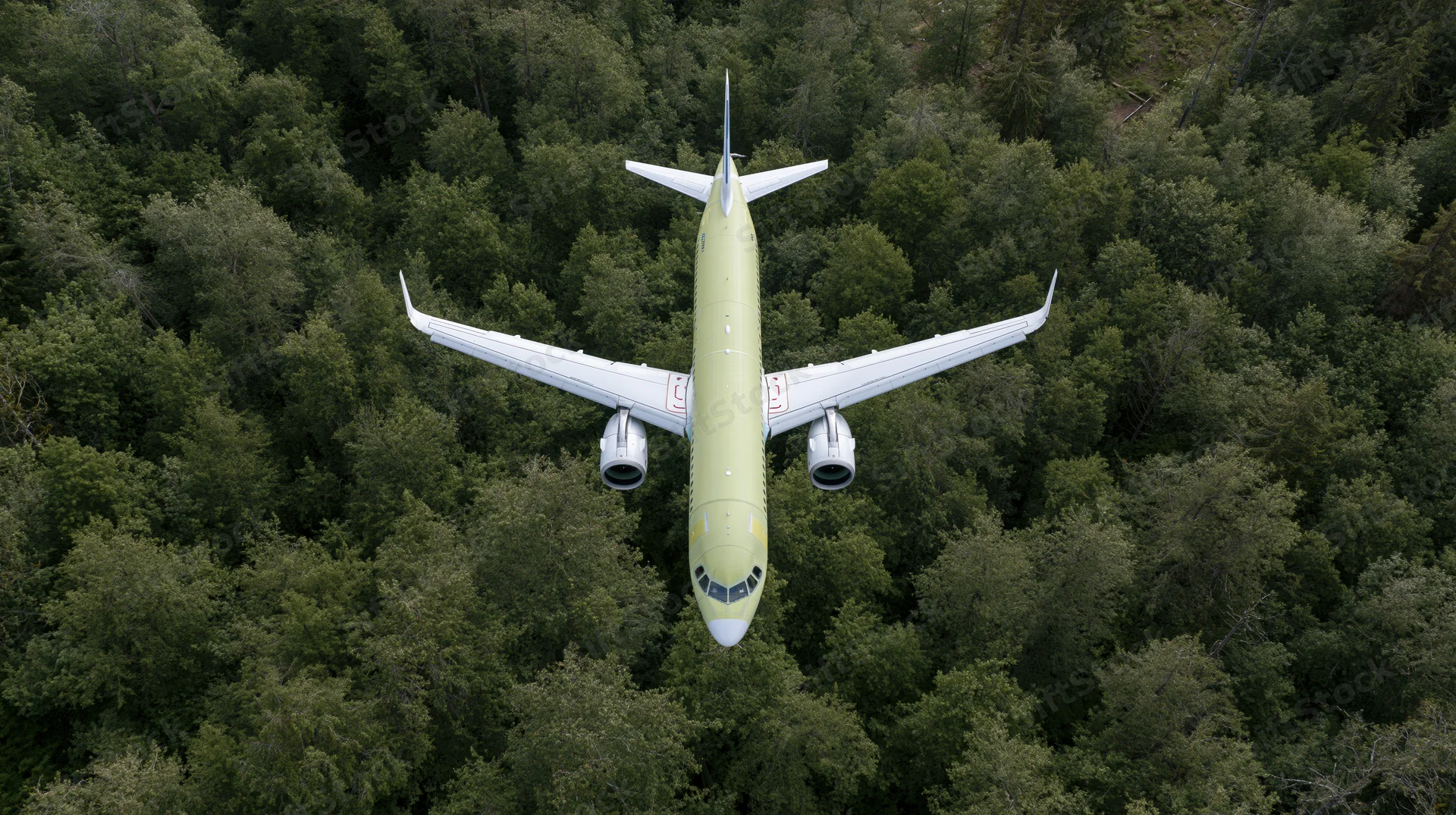 Commercial passenger airplane in lime green livery flying over dense forest canopy