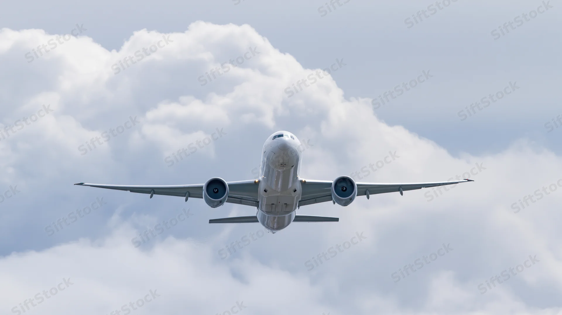 Commercial passenger jet flying through partly cloudy sky viewed from below