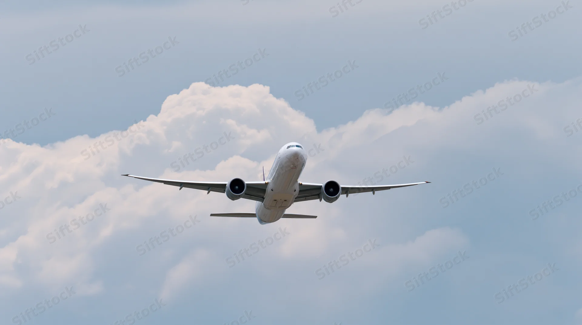 Commercial passenger jet flying through partly cloudy sky