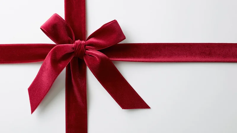 Deep red velvet ribbon tied in a bow across a white surface