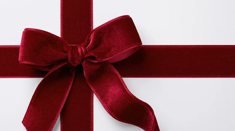 Deep red velvet ribbon tied in a bow across a white surface