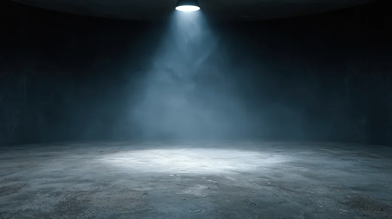 Spotlight beam illuminating concrete floor in dark empty studio interior
