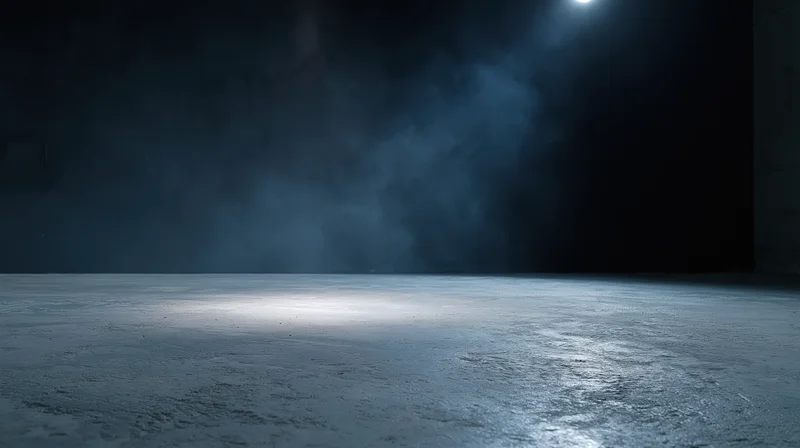 Spotlight on empty concrete floor in dark studio interior with smoke