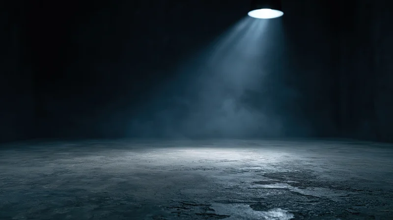 Spotlight beam illuminating concrete floor in dark empty studio interior