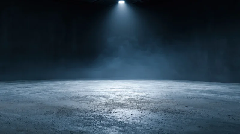 Spotlight illuminating a foggy concrete floor in a dark empty studio