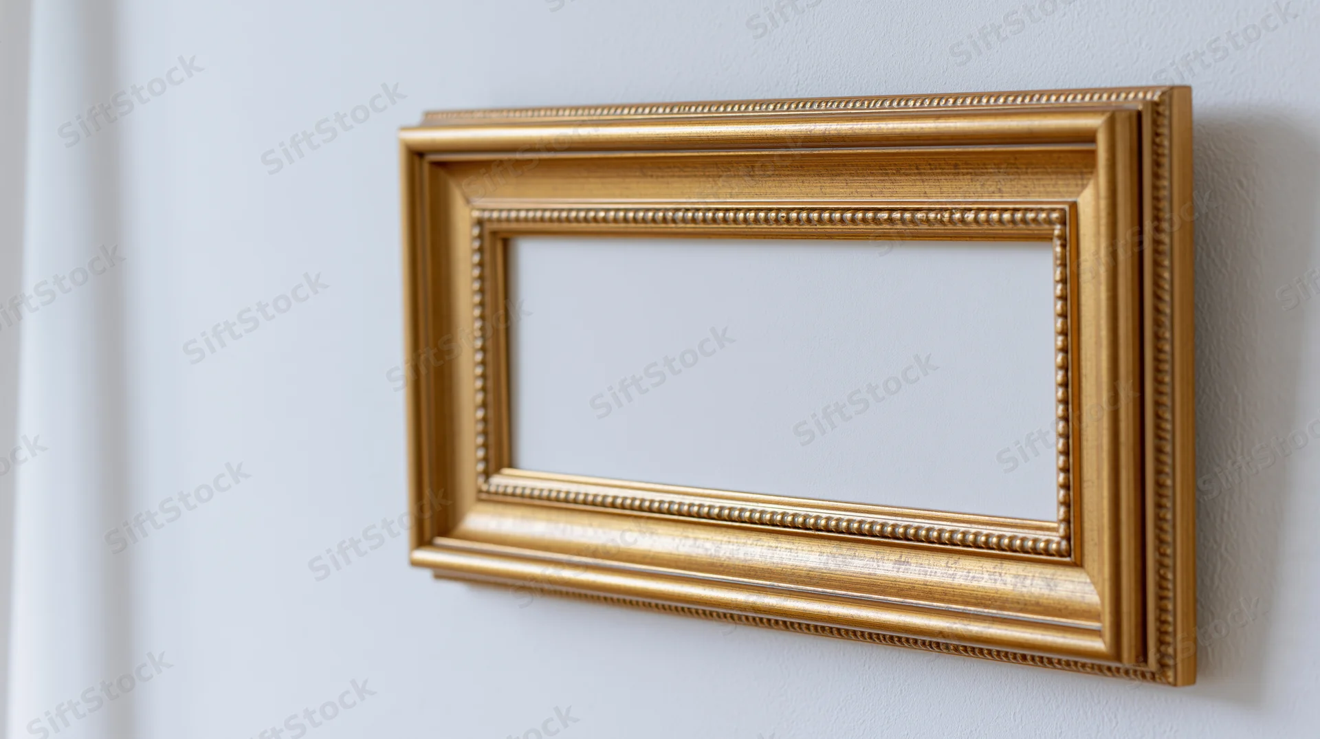 Ornate gold picture frame with detailed molding mounted on a white wall