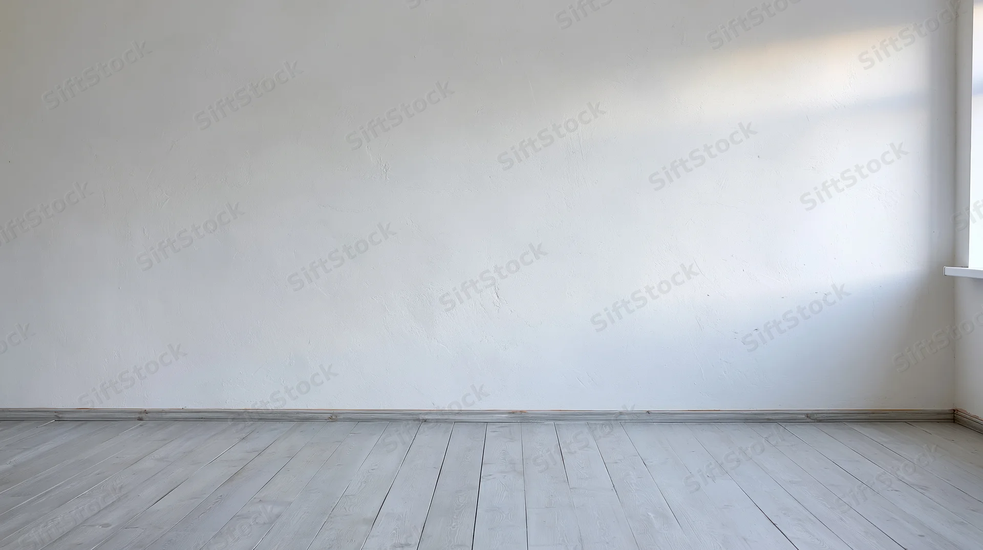 Empty room with white plaster wall and pale wood flooring near window