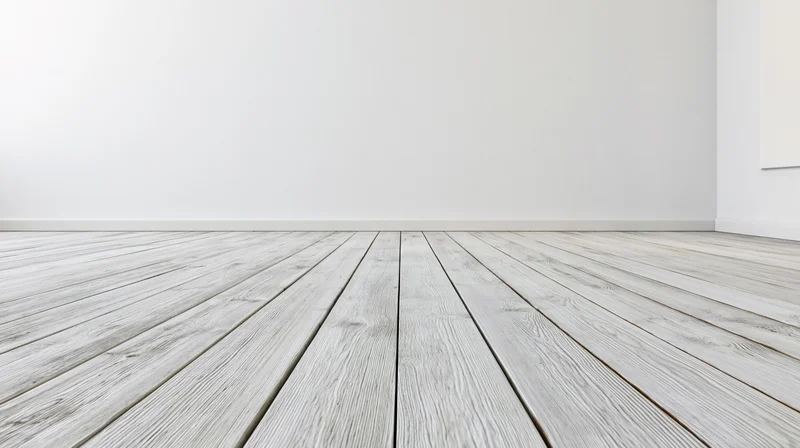 Empty room with whitewashed wooden plank floor receding into white walls