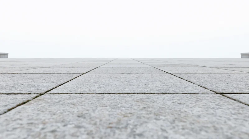 Low-angle view of light grey concrete tiles receding into the distance on an outdoor pavement