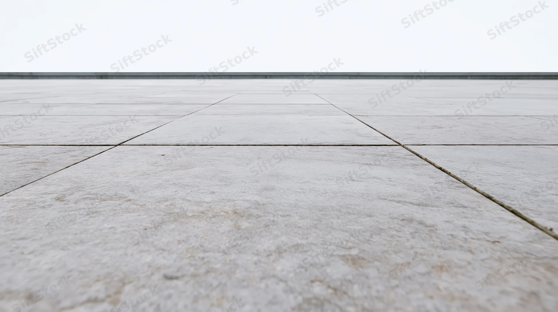 Light grey concrete tile floor receding into the distance under an overcast sky
