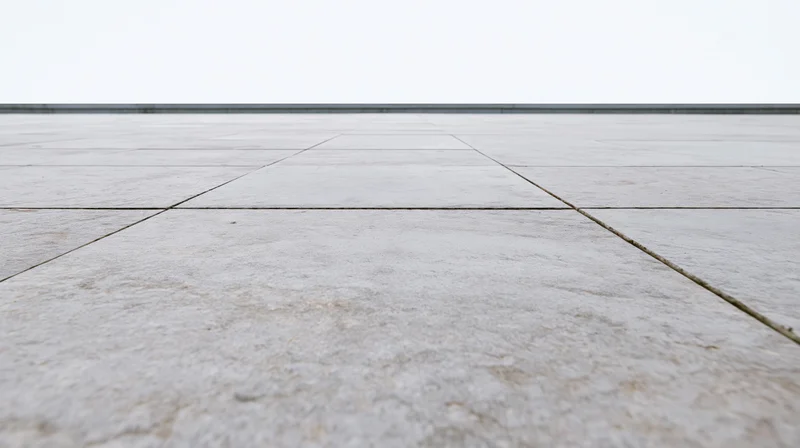 Light grey concrete tile floor receding into the distance under an overcast sky