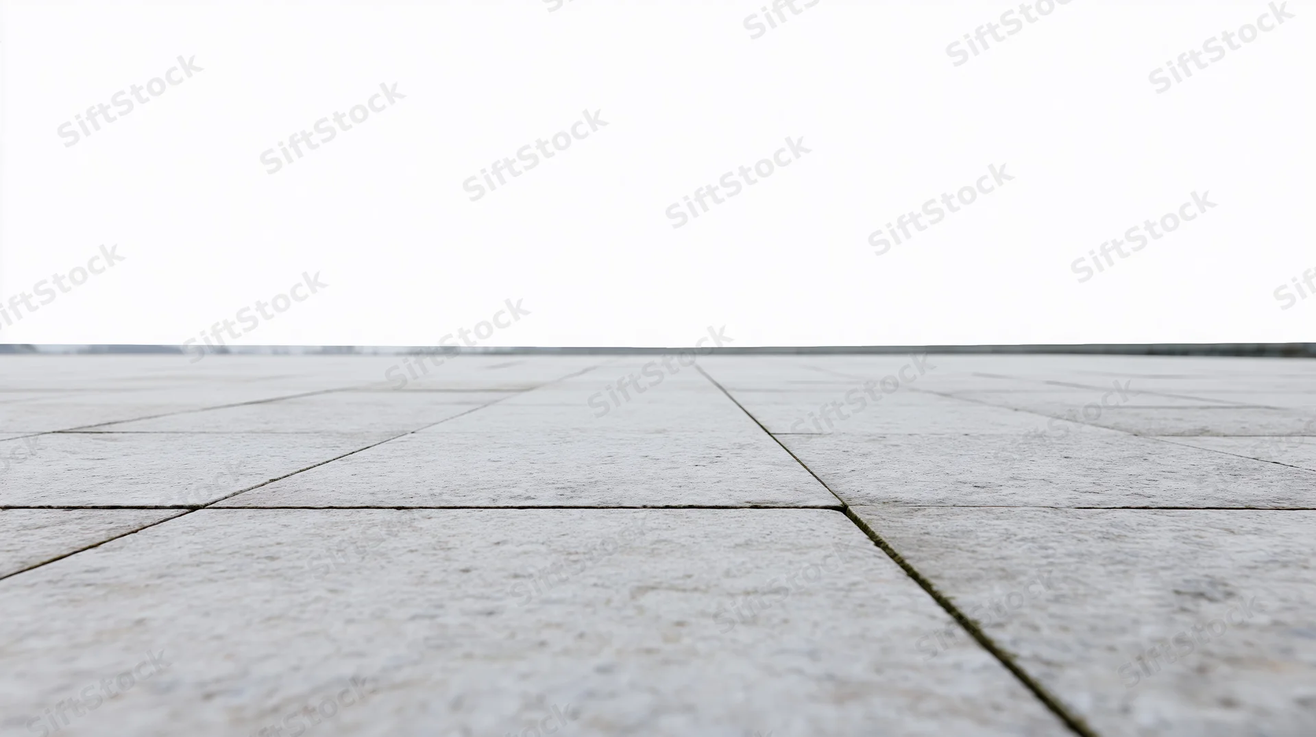 Light grey concrete tiles forming a receding outdoor floor surface under an overcast sky