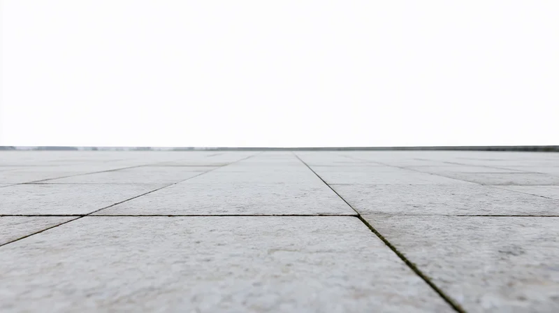 Light grey concrete tiles forming a receding outdoor floor surface under an overcast sky