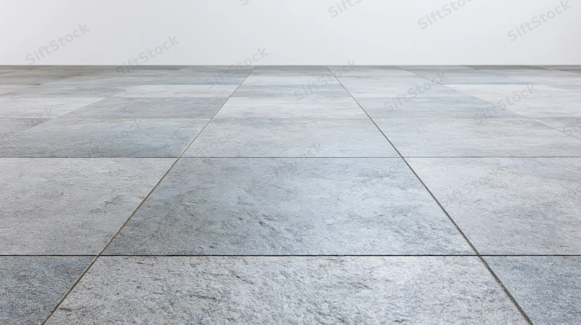 Light grey stone tile floor extending toward a plain white wall in an empty interior space