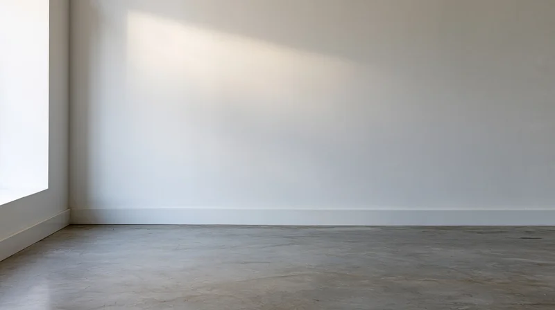 Empty minimalist room with white wall and concrete floor near window
