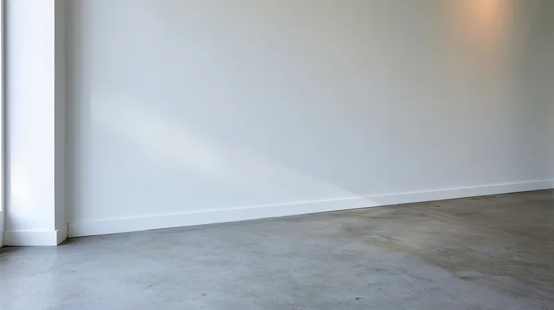 Empty minimalist room with white wall and concrete floor near a corner