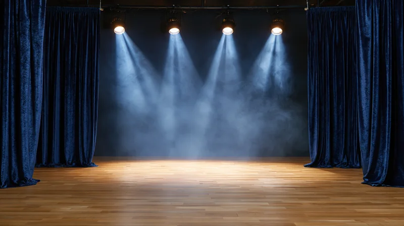 Empty theater stage with spotlights and blue velvet curtains, hardwood floor, smoke in the air