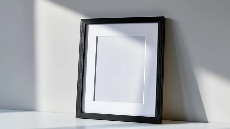 Empty black picture frame with white mat leaning against a white wall on a shelf
