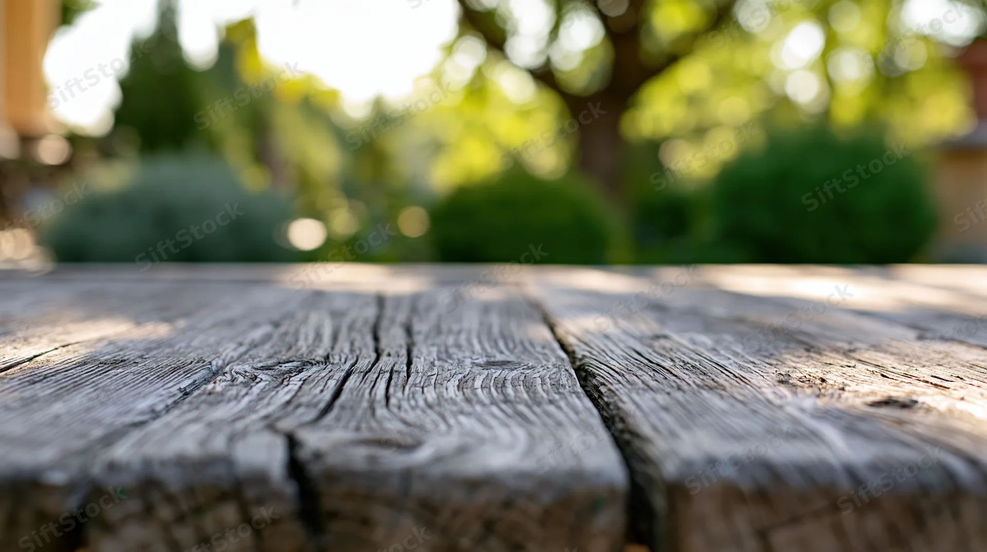 Weathered wooden tabletop in sharp focus with blurred green garden background