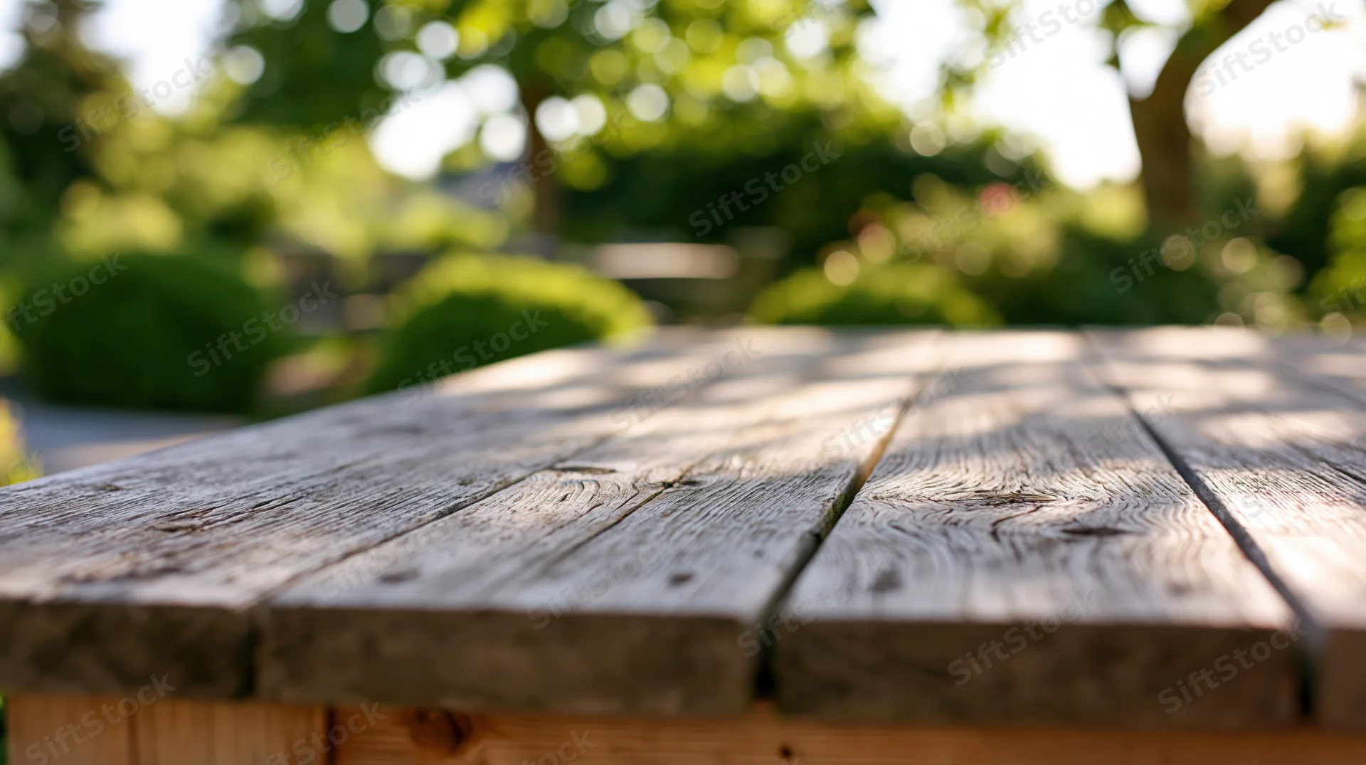 Weathered wooden tabletop in sharp focus with blurred green garden background