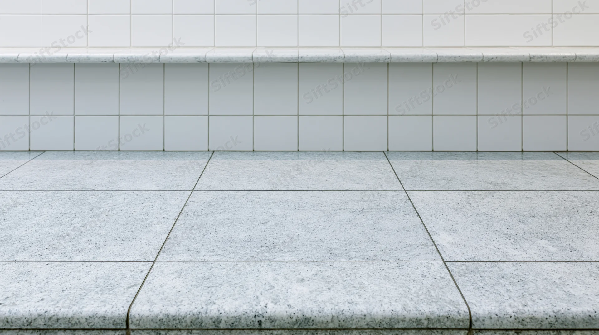 White granite tile floor meeting a white square-tiled wall in an interior space
