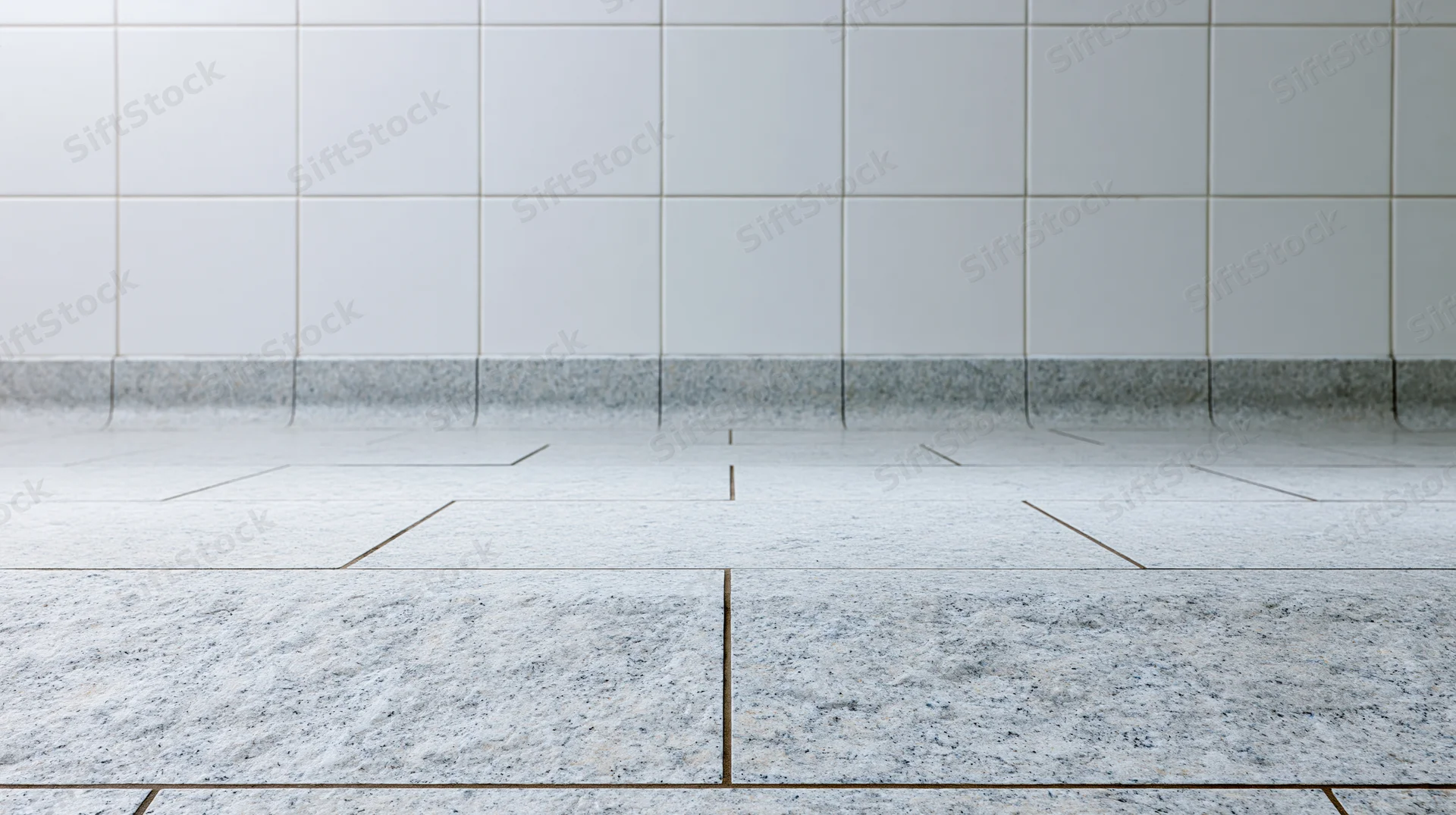 White granite tile floor meeting a white square-tiled wall in an interior space