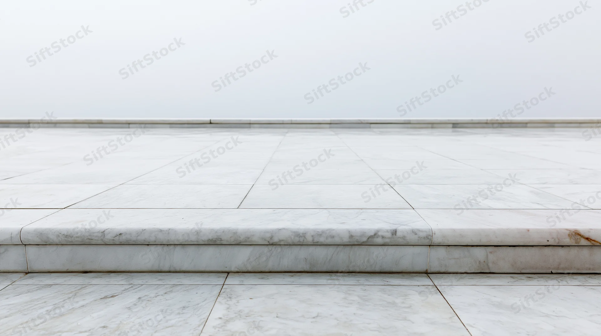 White marble tiled floor with low baseboard and step leading to open space