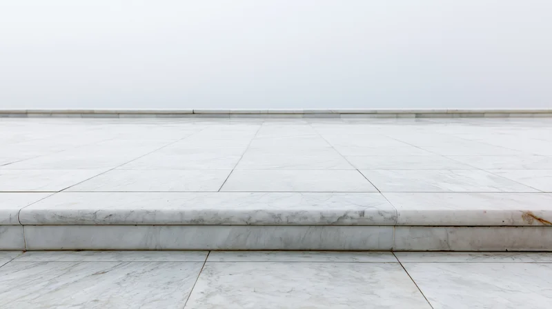 White marble tiled floor with low baseboard and step leading to open space