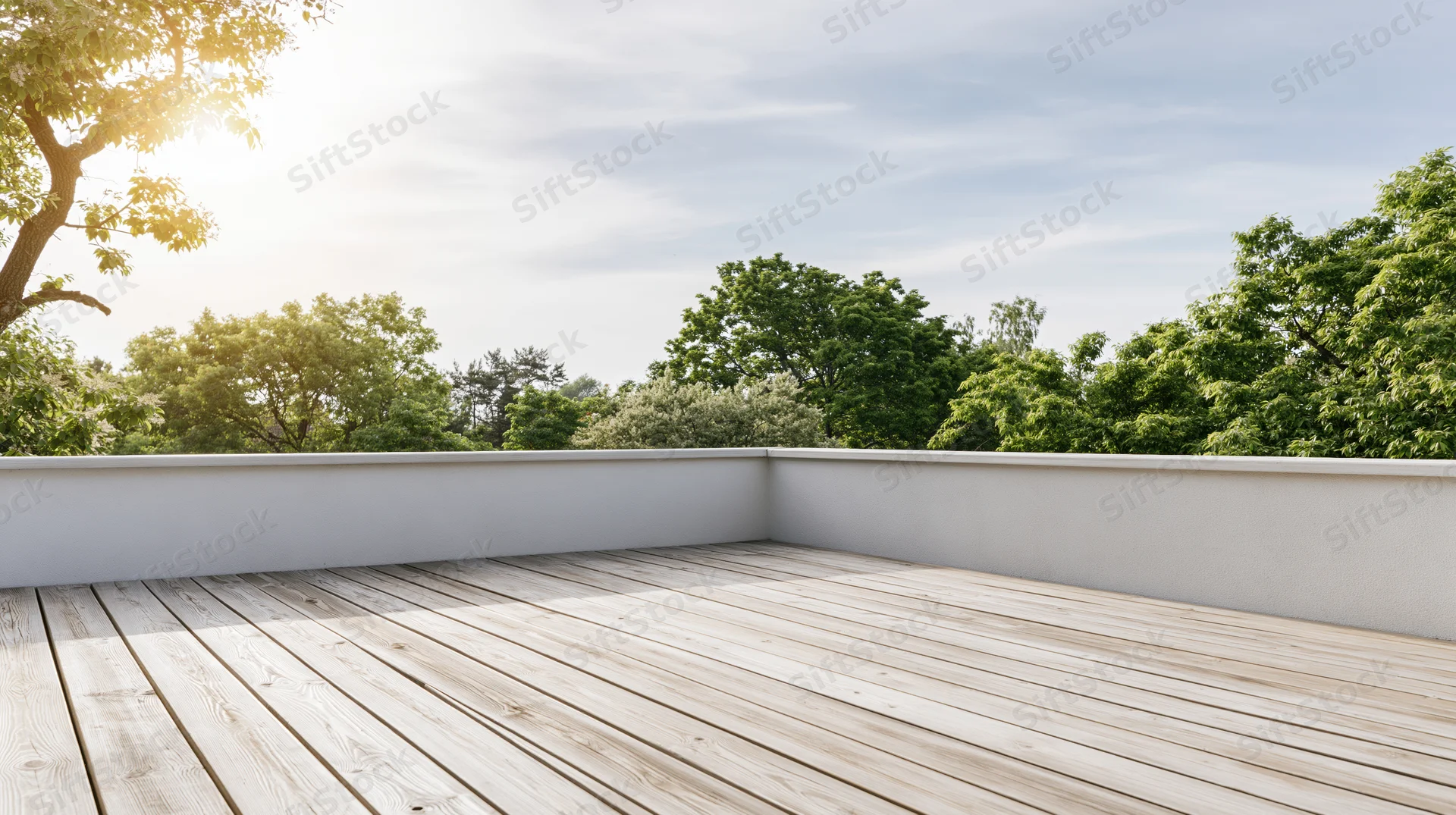 Empty wooden deck terrace with bleached planks and white walls overlooking green trees under a bright sky