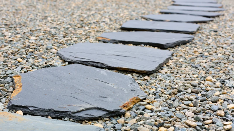Irregular slate stepping stones arranged diagonally across a gravel garden path