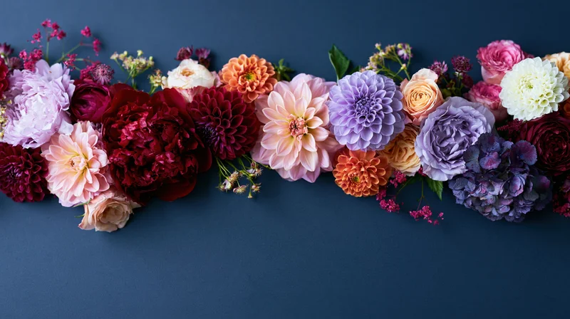 Mixed cut flowers arranged in a horizontal row on a dark blue surface