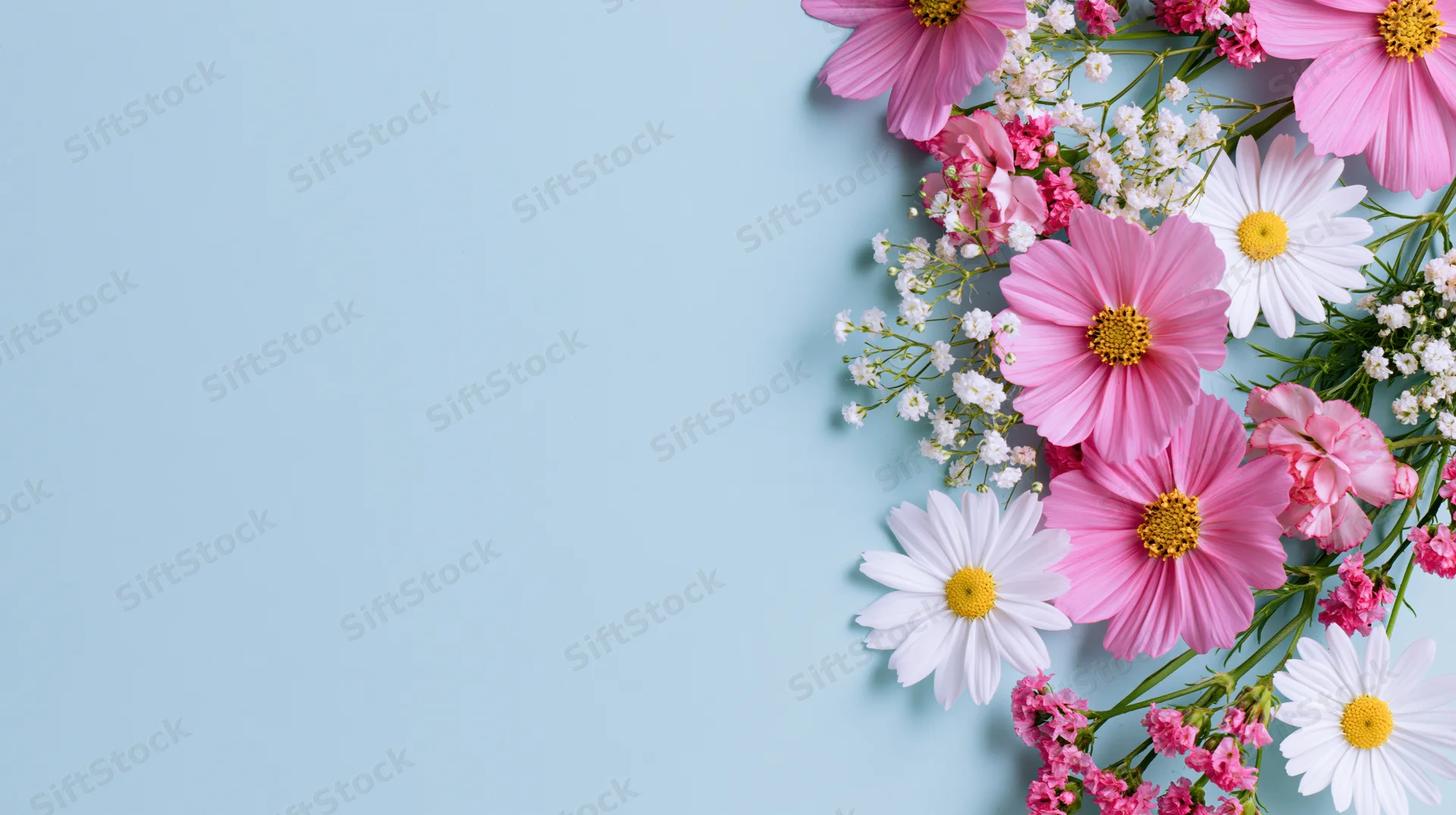 Mixed spring flowers arranged in flat lay on light blue background with copyspace