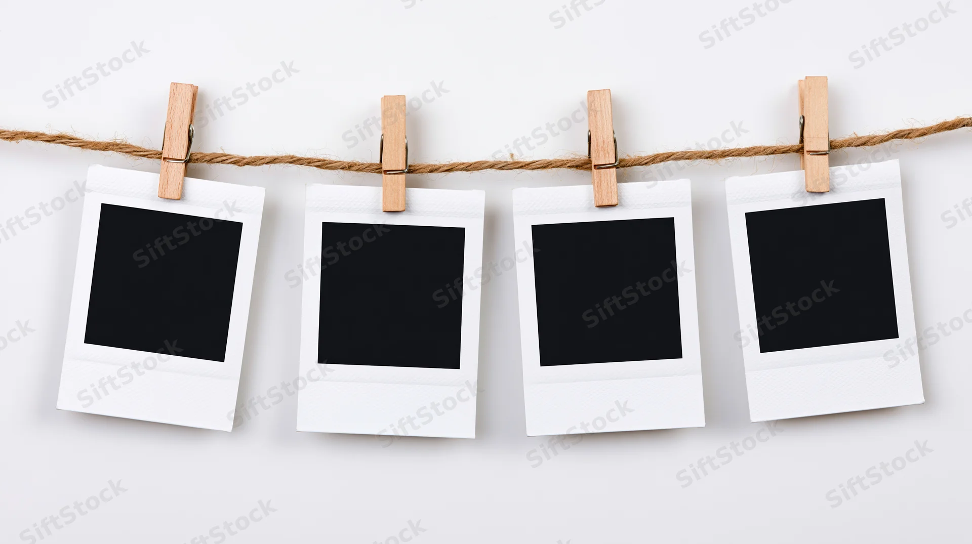 Four blank polaroid photo prints clipped to a twine line against white background