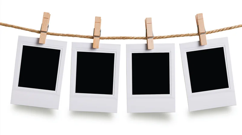 Four blank polaroid prints clipped to a rope with wooden clothespins against white background