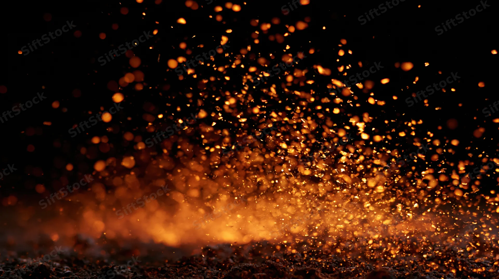 Glowing orange sparks rising from a dark surface against a black background