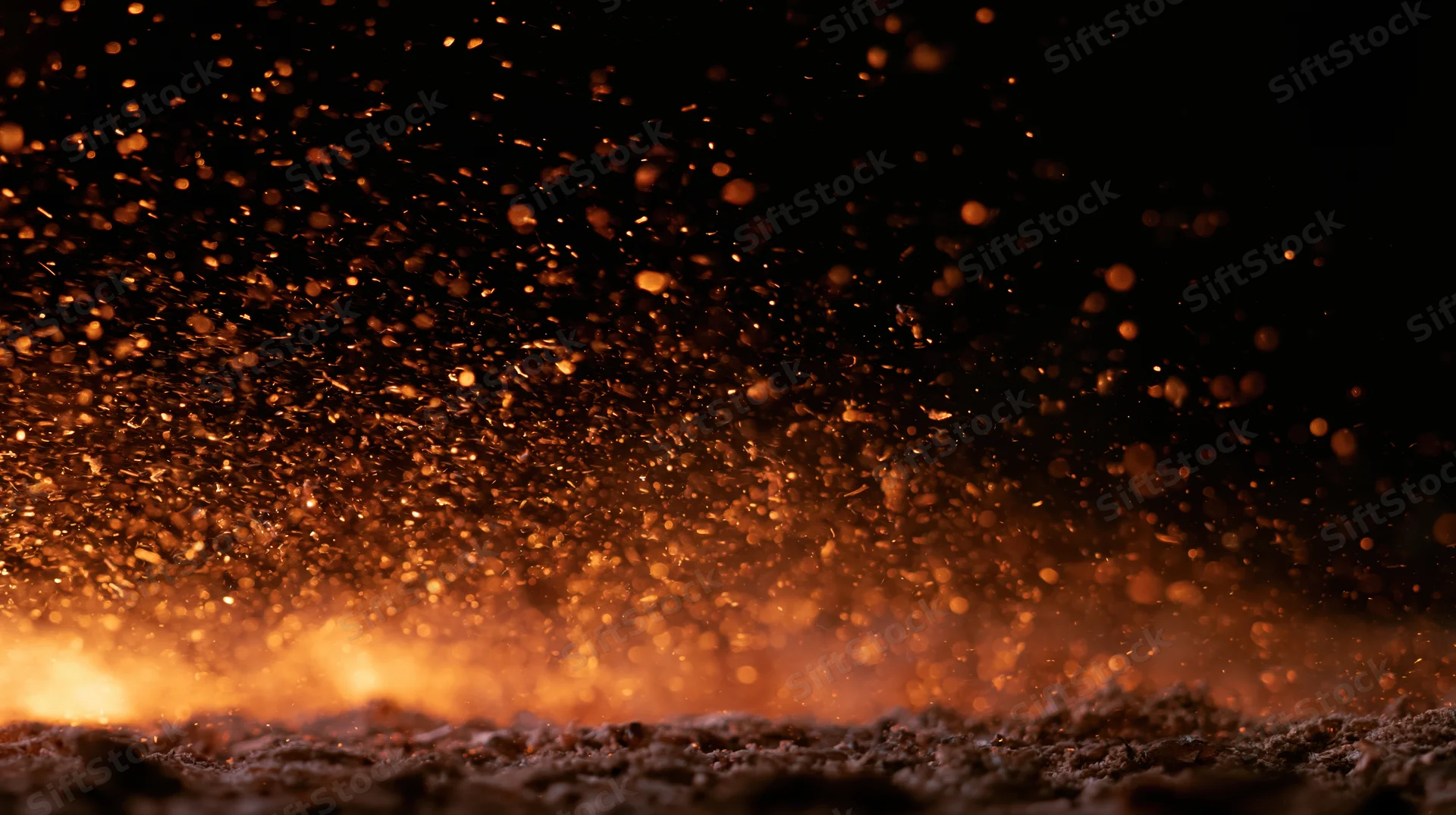 Glowing embers and sparks rising from a fiery base against a dark background