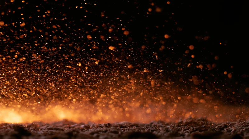 Glowing embers and sparks rising from a fiery base against a dark background