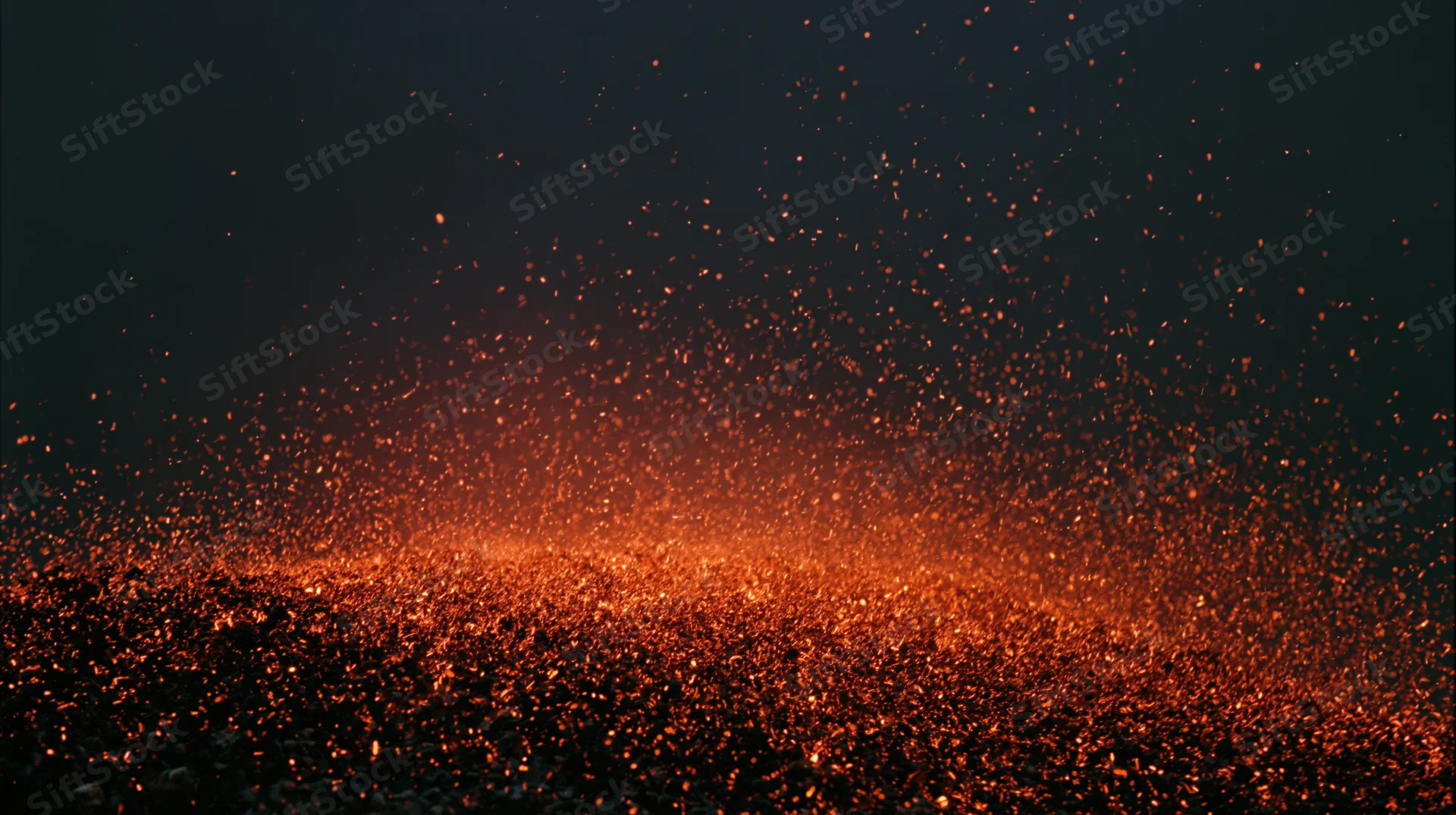 Glowing ember sparks rising upward in dark night sky