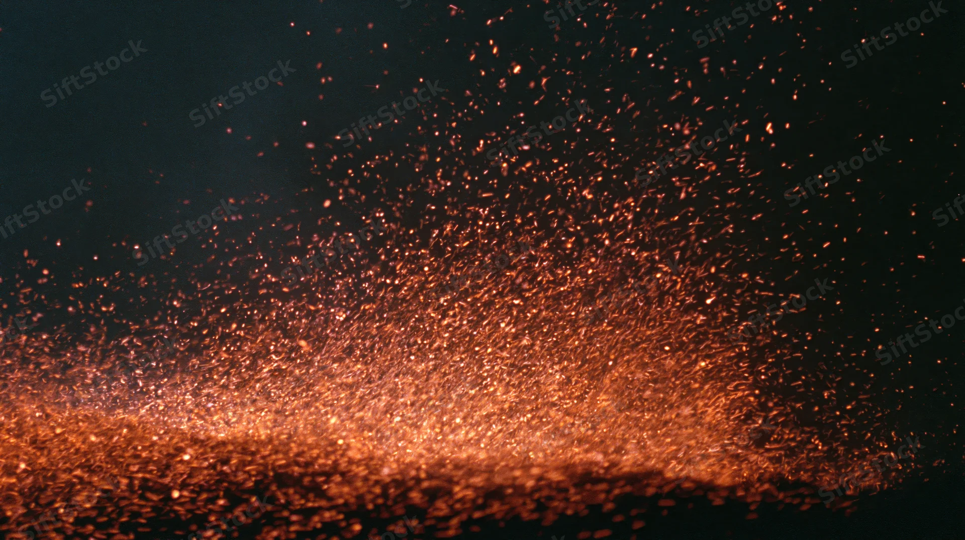 Glowing ember sparks rising upward against dark background