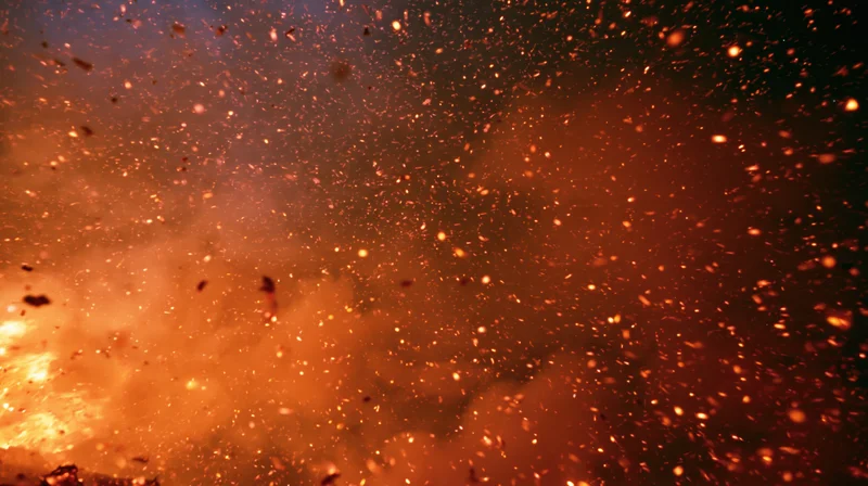 Glowing fire embers and sparks drifting upward in a fiery burst against a dark background