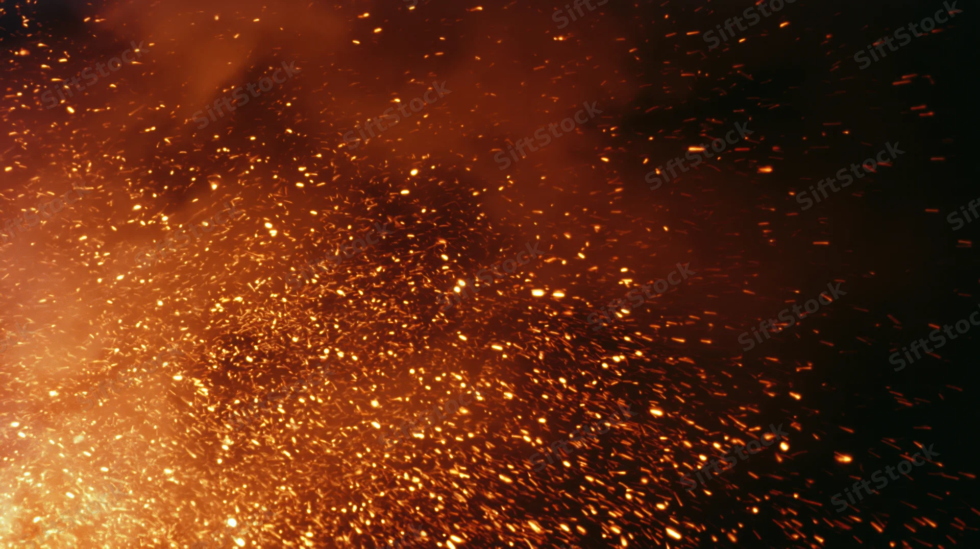 Glowing sparks and embers rising in dark night air