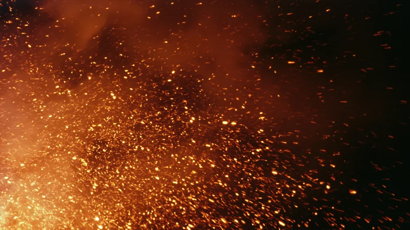 Glowing sparks and embers rising in dark night air