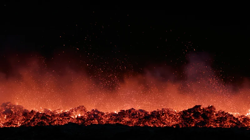 Glowing embers and sparks rising from a burning landscape at night