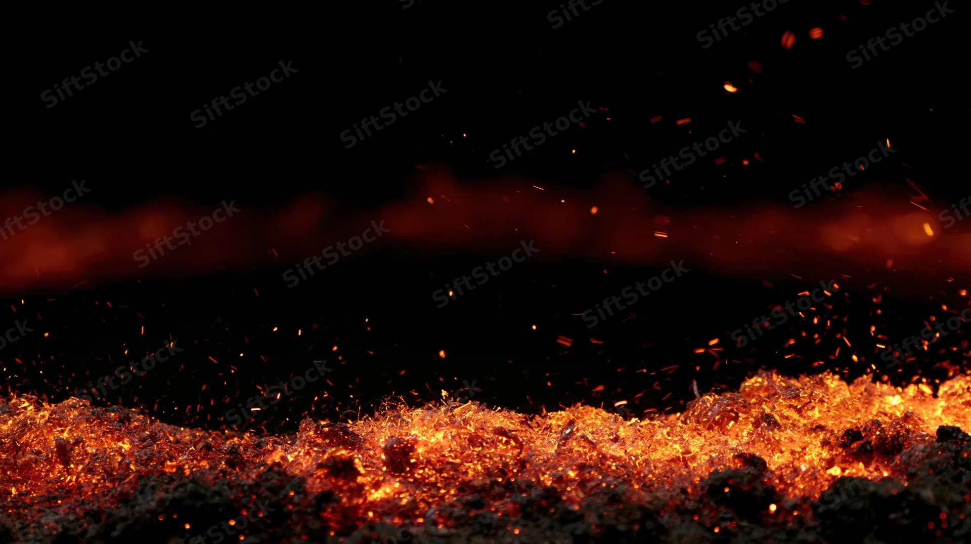Glowing embers and flying sparks against a dark background