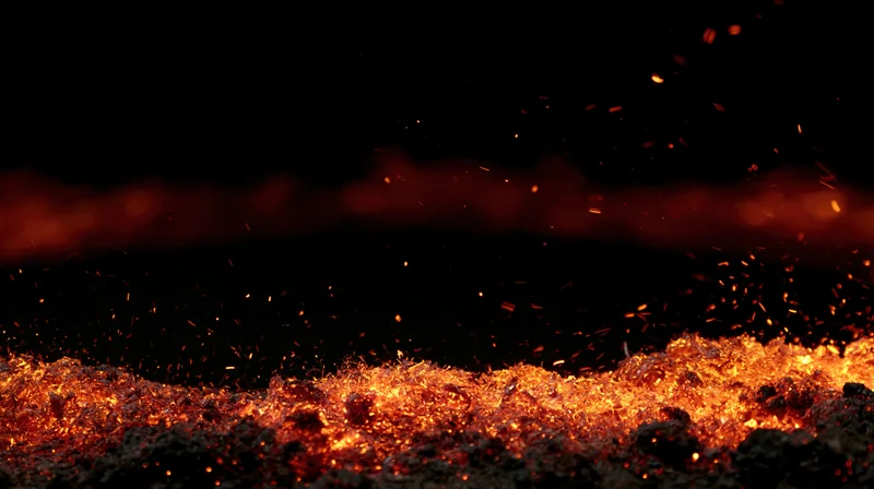 Glowing embers and flying sparks against a dark background